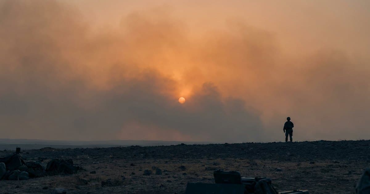 A lone soldier silhouette against a hazy, smoke-filled sky